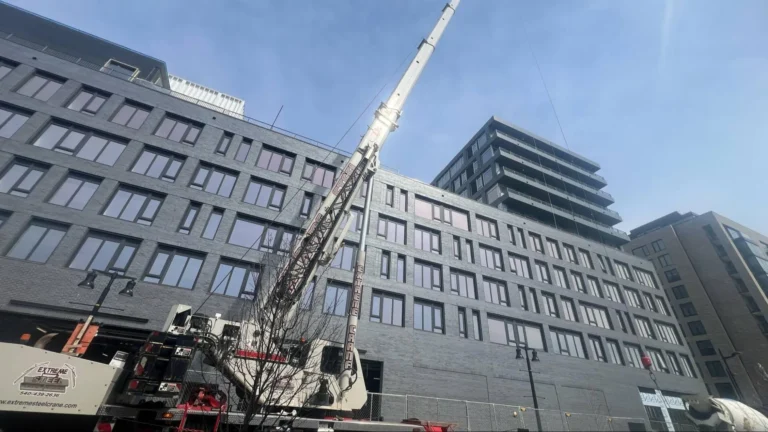 A crane set up in front of a gray building.